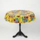Round yellow oilcloth tablecloth with colorful floral patterns on a bistro table in a garden - Casa Frida